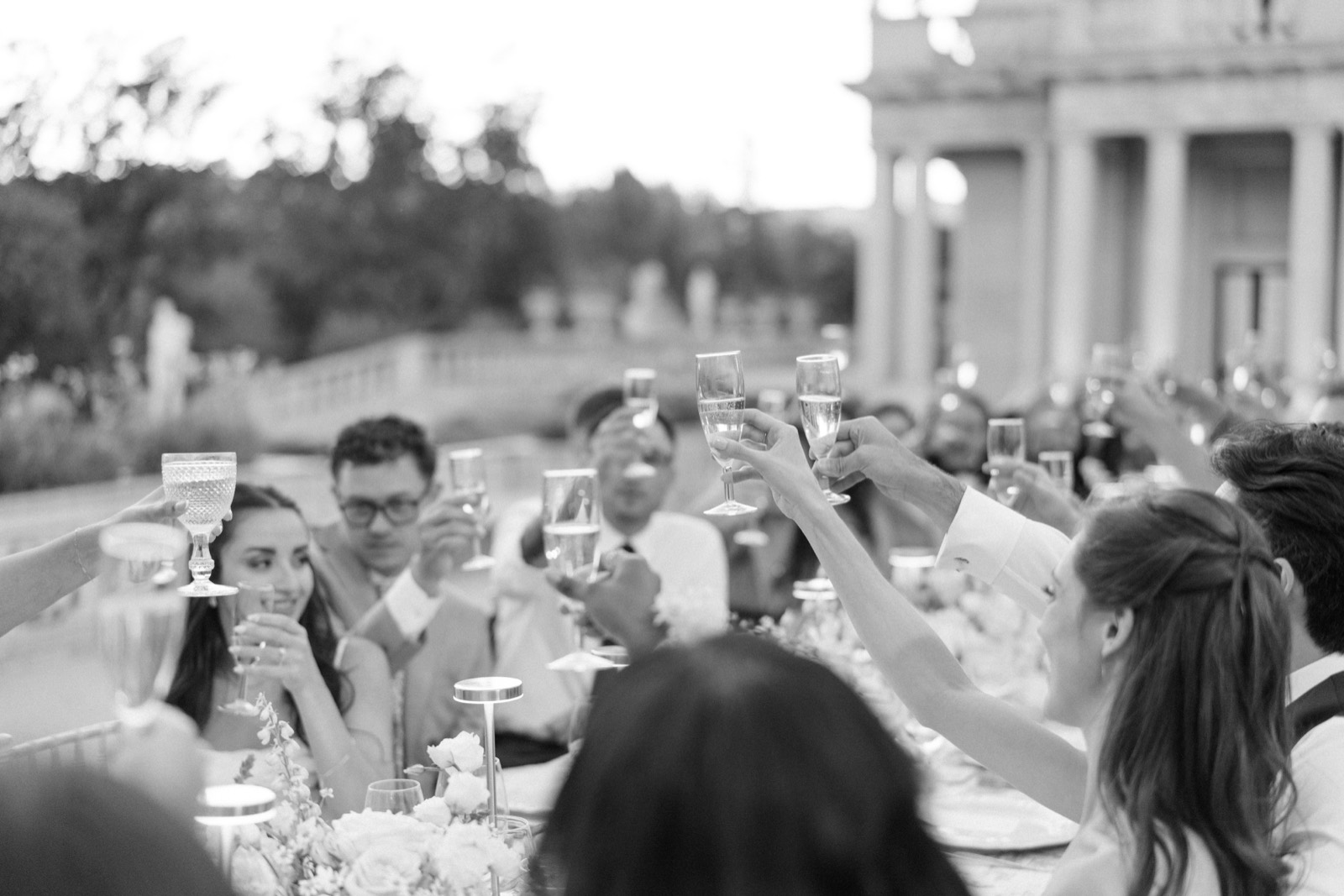 Black and white photo of guests raising their glasses in a toast